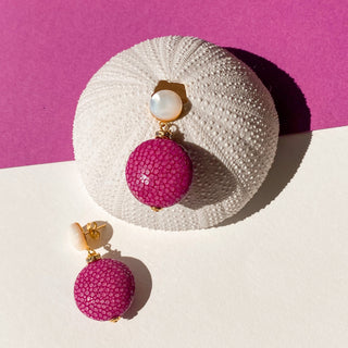 Boucles d'oreilles pendantes en galuchat rose et nacre blanche, finition dorée à l'or fin 24 carats, pour oreilles percées et clips, photo posée pour voir le détail.