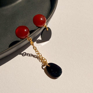 Boucles d’oreilles dépareillées Gaspard, duo agate noire et cornaline, style moderne et graphique, pour oreilles percées et clips, photo posée.