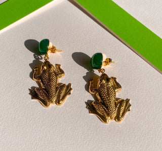 Détail posé de boucles d'oreilles grenouille dorées pour oreilles percées ou clips