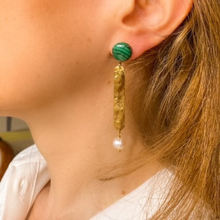Boucles d’oreilles Cléo pendantes dorées en malachite verte et perles blanches portées de profil, montrant la longueur, l’éclat de la dorure et les nuances vertes des pierres naturelles, disponibles en percées ou clips.
