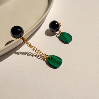Boucles d’oreilles dépareillées Gaspard  agate noire et malachite, monture dorée à l’or fin 24k, pour oreilles percées ou clips pour oreilles non percées, photo posée.
