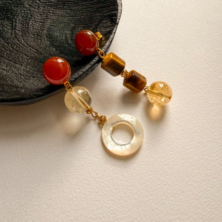 Boucles d'oreilles dépareillées clips et oreilles percées avec des pierres naturelles, œil de tigre, photo posée.