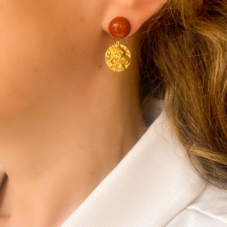 Boucles d’oreilles Doris pendantes dorées en jaspe rouge portées, montrant la longueur, le mouvement et l’intensité de la pierre, disponibles en percées ou clips.