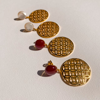 Boucles d’oreilles Flavie en nacre blanche et doré, détail posé mettant en valeur la nacre blanche et la cornaline rouge, les nuances et la finition dorée, disponibles en version percées ou clips.