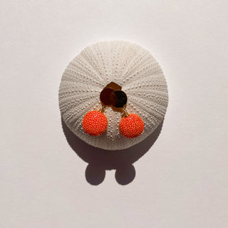 Boucles d’oreilles Gala en galuchat orange, détail posé mettant en valeur la texture du galuchat et la finition dorée à l’or fin 24 carats.