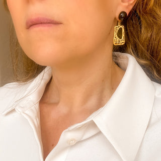 Boucles d’oreilles Gustave pendantes dorées style Art Déco en agate noire portées, montrant la longueur de 4 cm, les lignes géométriques et l’éclat de la dorure, disponibles en percées ou clips.