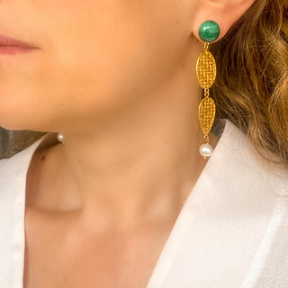 Boucles d’oreilles pendantes Liz XXL dorées en malachite et perles naturelles portées de profil, montrant la longueur, le mouvement et l’éclat des pierres, disponibles en percées ou clips.