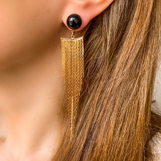 Boucles d’oreilles Niagara pendantes dorées en agate noire portées, montrant la longueur, le mouvement et le contraste de la pierre, disponibles en percées ou clips.