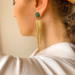 Boucles d’oreilles Niagara pendantes dorées en malachite verte portées de profil, montrant la longueur, l’éclat de la dorure et les nuances naturelles de la pierre, disponibles en percées ou clips.