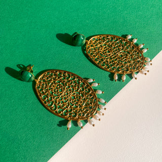 Boucles d’oreilles Scarlett pendantes dorées, détail posé mettant en valeur la malachite verte, les perles naturelles et la finition dorée.