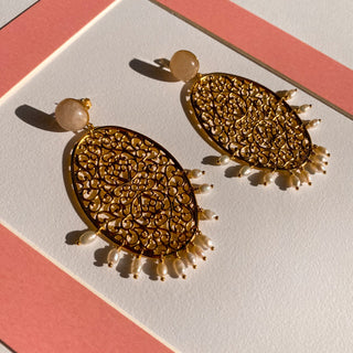 Boucles d’oreilles Scarlett pendantes dorées, détail posé mettant en valeur le quartz rose, les perles et la finition dorée. Disponibles pour oreilles percées ou clips.