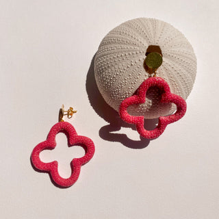 Boucles d’oreilles Trèfle en galuchat rose, détail posé mettant en valeur la texture du galuchat, la forme trèfle et la finition dorée à l’or fin 24 carats.  