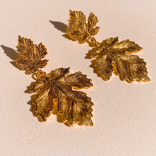 Boucles d’oreilles Xylia dorées à l’or fin 24 carats, détail posé mettant en valeur la texture, la forme feuille et la finition dorée.