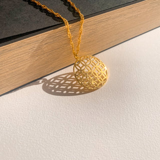 Collier Flavie doré, détail posé mettant en valeur la texture , l forme du pendentif et la finition doré.