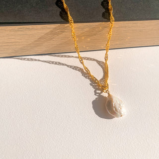 Collier Lou doré, détail posé mettant en valeur la texture, la perle et la finition dorée.