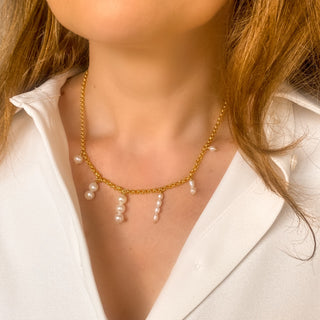 Détail porté du collier doré Liv avec perles blanches.