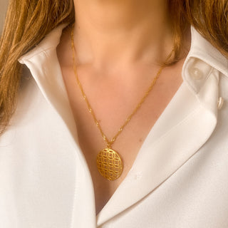 Collier doré avec pendentif graphique, porté vue de face.