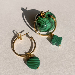 Zoom sur les créoles dépareillées dorées en malachite avec charms en trèfle et cœur