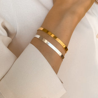 Joncs Ana dorés et argentés portés, montrant le design fin et graphique, l’éclat de la dorure et de l'argenture et la finesse du bracelet.