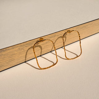 Boucles d’oreilles Eliott grand rectangle doré Youm, finition or fin 24 carats, posé pour montrer le détail de la dorure.