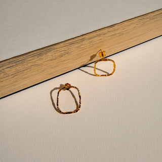 Boucles d’oreilles Maïl petit rectangle doré Youm, finition or fin 24 carats, posé pour montrer le détail de la dorure.