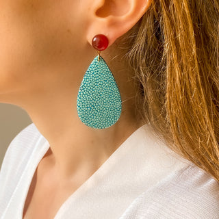 Boucles d’oreilles Acqua en galuchat turquoise portées, montrant la longueur totale de 7 cm et la largeur de 3 cm, avec pierre cornaline, disponibles en percées ou clips.