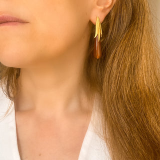 Boucles d’oreilles Armelle pendantes dorées en agate rouge portées, montrant la longueur, l’éclat de la dorure et la profondeur de la pierre.