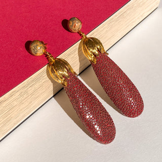 Boucles d’oreilles Ava en galuchat bordeaux, détail posé mettant en valeur la texture du galuchat, la pierre naturelle jaspe léopard et la finition dorée à l’or fin 24 carats.