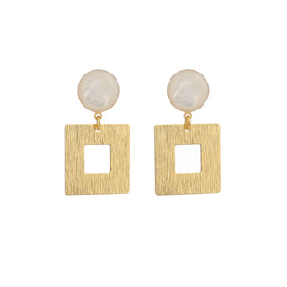 Boucles d’oreilles Claude dorées et nacre blanche, packshot sur fond neutre, disponibles en version percées ou clips.