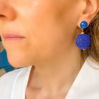 Boucles d’oreilles Grace en galuchat bleu, détail posé mettant en valeur la texture du galuchat, la pierre agate bleue et la finition dorée à l’or fin 24 carats.