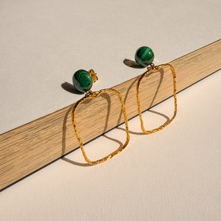 Boucles d’oreilles Gino rectangle doré avec pierre naturelle malachite Youm, finition or fin 24 carats, pour oreilles percées ou non percées clips, posé pour montrer le détail de la dorure et de la malachite.