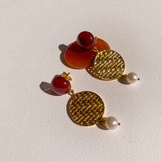Boucles d’oreilles Romy pendantes dorées, détail posé mettant en valeur la cornaline, les perles et la finition dorée, disponibles en version percées ou clips.