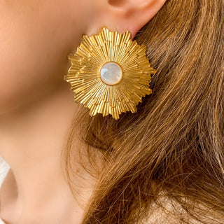 Boucles d’oreilles Soléa clips dorées en forme de soleil avec nacre blanche portées, montrant la brillance, la taille et le design solaire.
