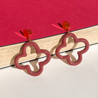 Boucles d’oreilles Trèfle en galuchat bordeaux, détail posé mettant en valeur la texture du galuchat, la forme trèfle et la finition dorée à l’or fin 24 carats.