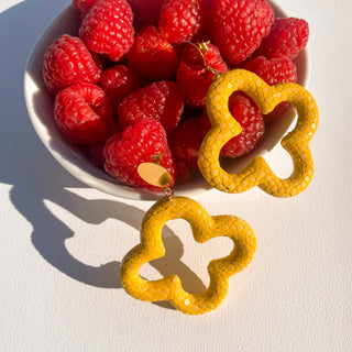 Boucles d’oreilles Trèfle en galuchat jaune, détail posé mettant en valeur la texture du galuchat, la forme trèfle et la finition dorée à l’or fin 24 carats.  