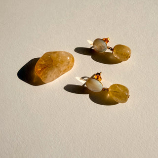 Boucles d’oreilles Zénon dorées, détail posé mettant en valeur les pierres naturelles, rutile jaune et la nacre blanche et la finition en or fin 24 carats.