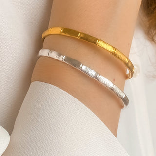 Jonc Bambou doré et argenté portés, bracelet rigide ajustable en laiton doré à l’or fin 24 carats, style minimaliste et intemporel.