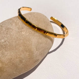 Jonc Bambou doré, détail posé mettant en valeur la texture bambou et la finition dorée à l’or fin 24 carats.