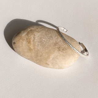 Jonc Empreinte argenté, détail posé mettant en valeur la texture empreinte et la finition argentée brillante.