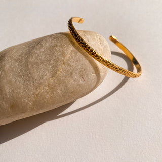 Jonc Empreinte doré, détail posé mettant en valeur la texture empreinte et la finition dorée à l’or fin 24 carats.