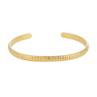 Jonc Empreinte doré en laiton doré à l’or fin 24 carats, texture empreinte, packshot sur fond neutre.