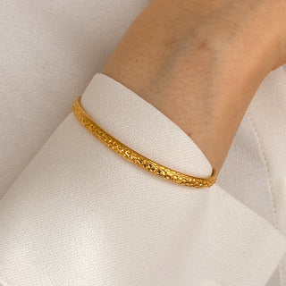 Jonc Empreinte doré porté détail, bracelet rigide ajustable en laiton doré à l’or fin 24 carats, style minimaliste et intemporel.