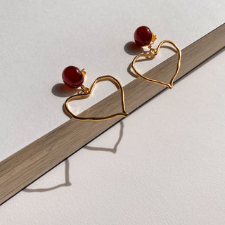 Zoom sur la texture et le motif es boucles d'oreilles cœur Mina dorée et cornaline rouge