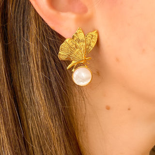 Boucles d’oreilles Chiara papillon dorées en nacre blanche de profil, montrant la finesse du motif, l’éclat de la nacre et le style délicat.