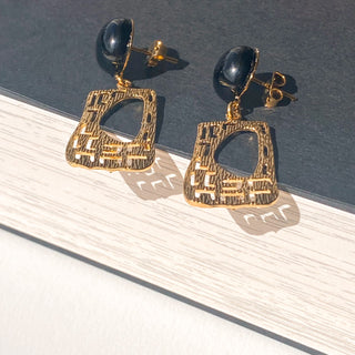 Boucles d’oreilles Gustave dorées, zoom détail posé mettant en valeur l’agate noire, la structure Art Déco et la finition en or fin 24 carats.