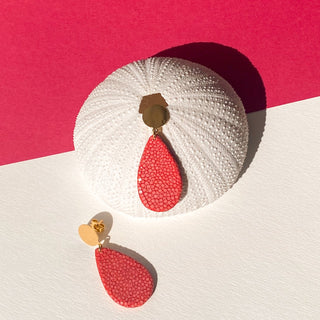 Boucles d’oreilles Gema en galuchat rose corail, détail posé mettant en valeur la texture du galuchat et la finition dorée à l’or fin 24 carats.