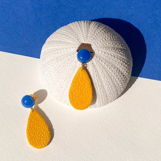 Boucles d’oreilles Gil en galuchat jaune, détail posé mettant en valeur la texture du galuchat, la pierre agate bleue et la finition dorée à l’or fin 24 carats.