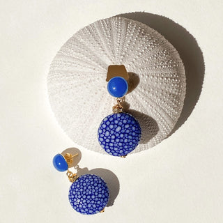 Boucles d’oreilles Grace en galuchat bleu, détail posé mettant en valeur la texture du galuchat, la pierre agate bleue et la finition dorée à l’or fin 24 carats.