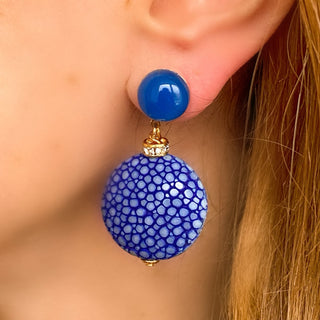Boucles d’oreilles Grace en galuchat bleu portées, montrant la longueur totale de 4,5 cm et la largeur de 2,8 cm, avec pierre agate bleue, disponibles en percées ou clips.