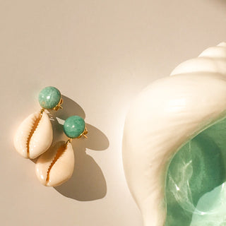 Boucles d’oreilles Océane dorées, détail posé mettant en valeur le coquillage cauri, l’amazonite et la finition en or fin 24 carats.